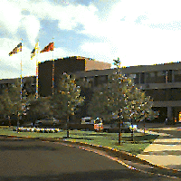 view of parking lot and 3 flags in front of building