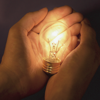lighted bulb in front of hand palm